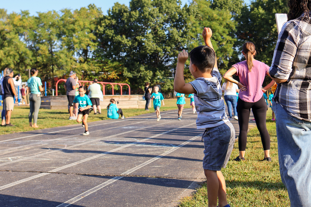 a boy cheers on the sidelines of an outdoor track