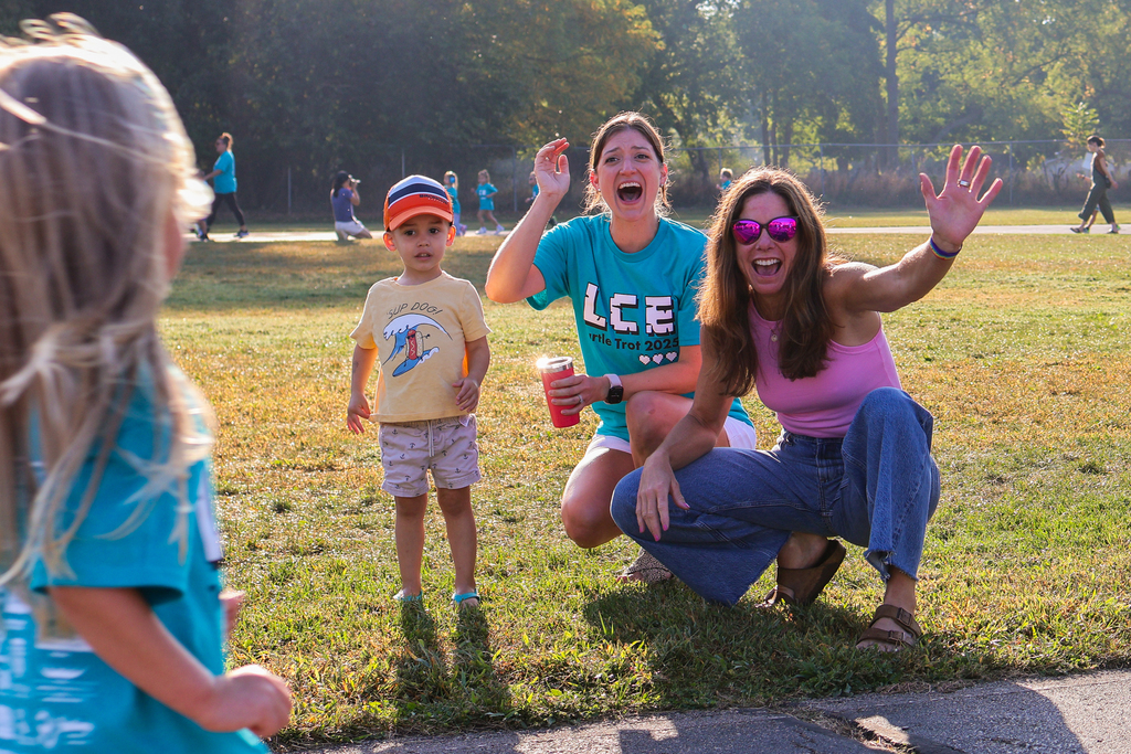 a family cheers for their child as they run by on an outdoor track