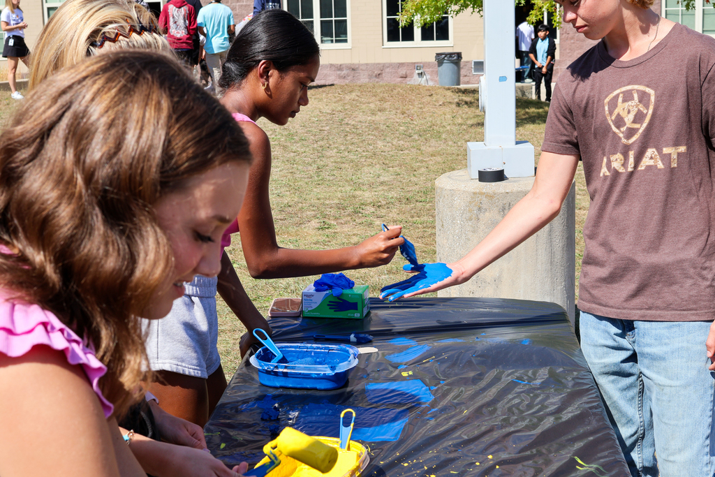 a girl paints blue paint on a boy's hand