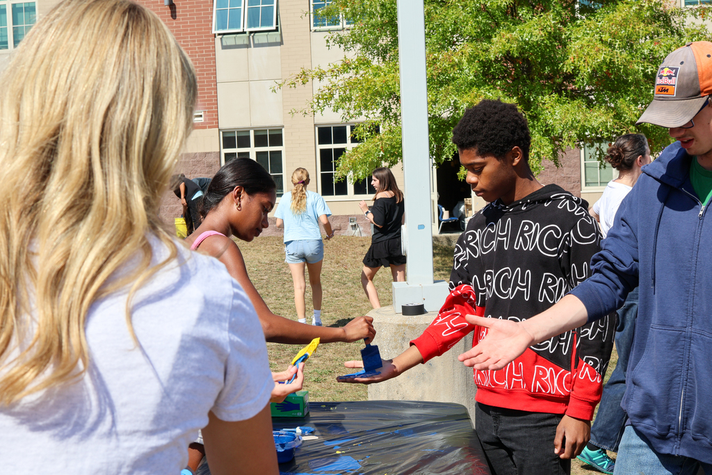 a girl paints blue paint on a boy's hand