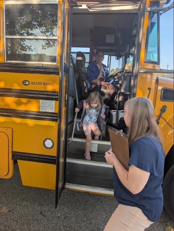 A litle girl getting off the bus.