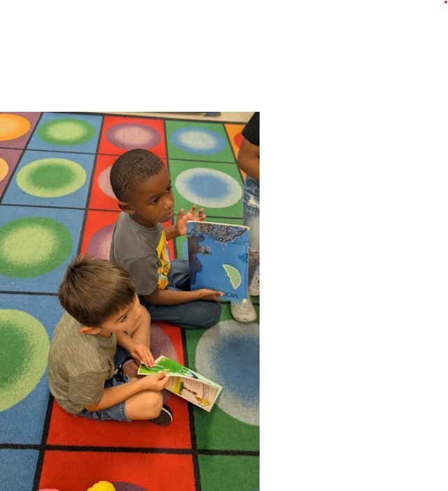 Two students sitting at the rug together.