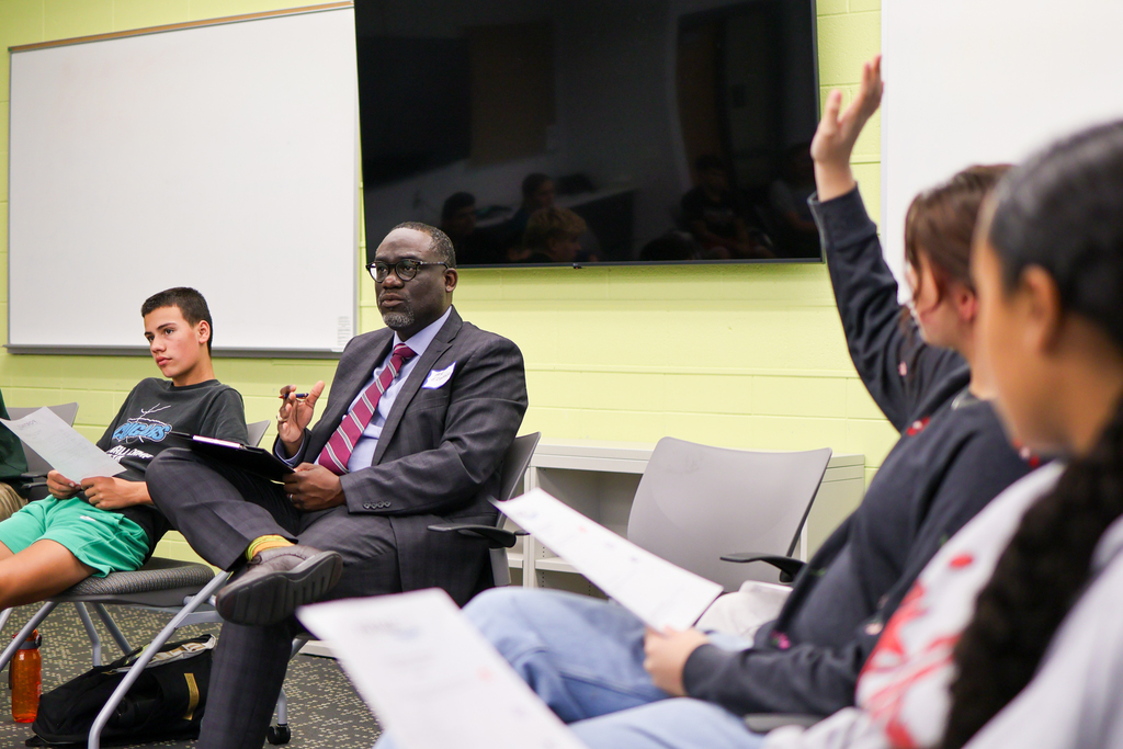 a man speaks to a group of high schoolers sitting in a conference room