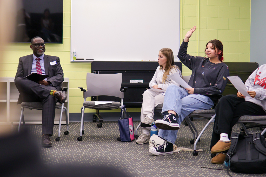 a man speaks to a group of high schoolers sitting in a conference room
