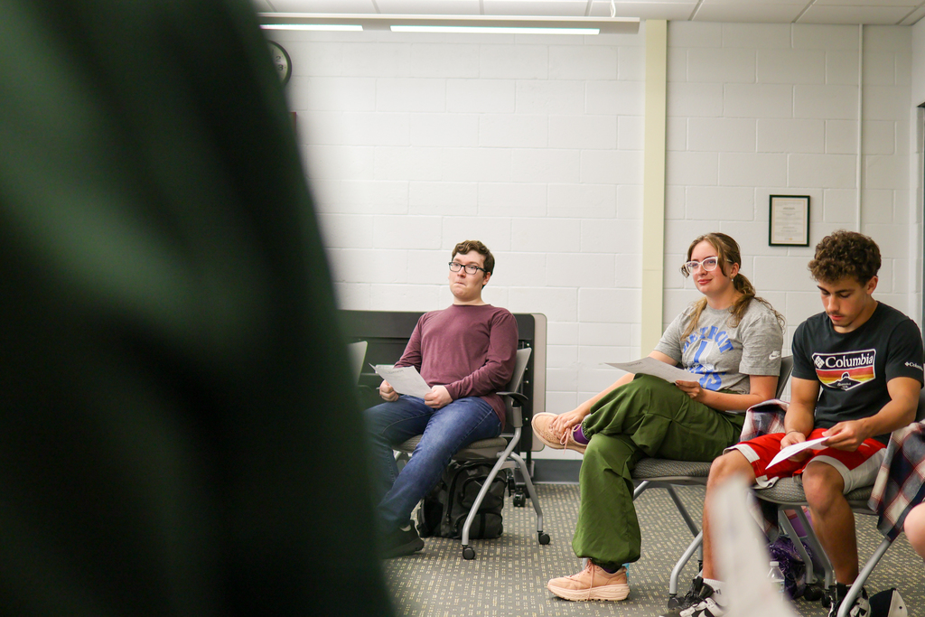 students sitting in a circle in a conference room listen