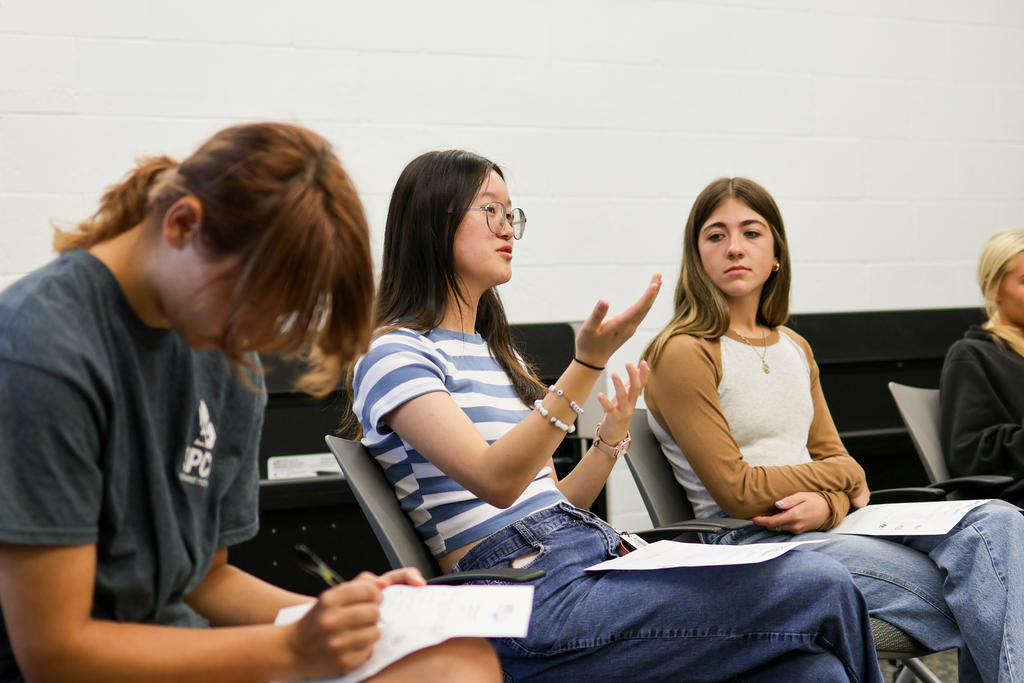 a girl speaks to her peers in a conference room