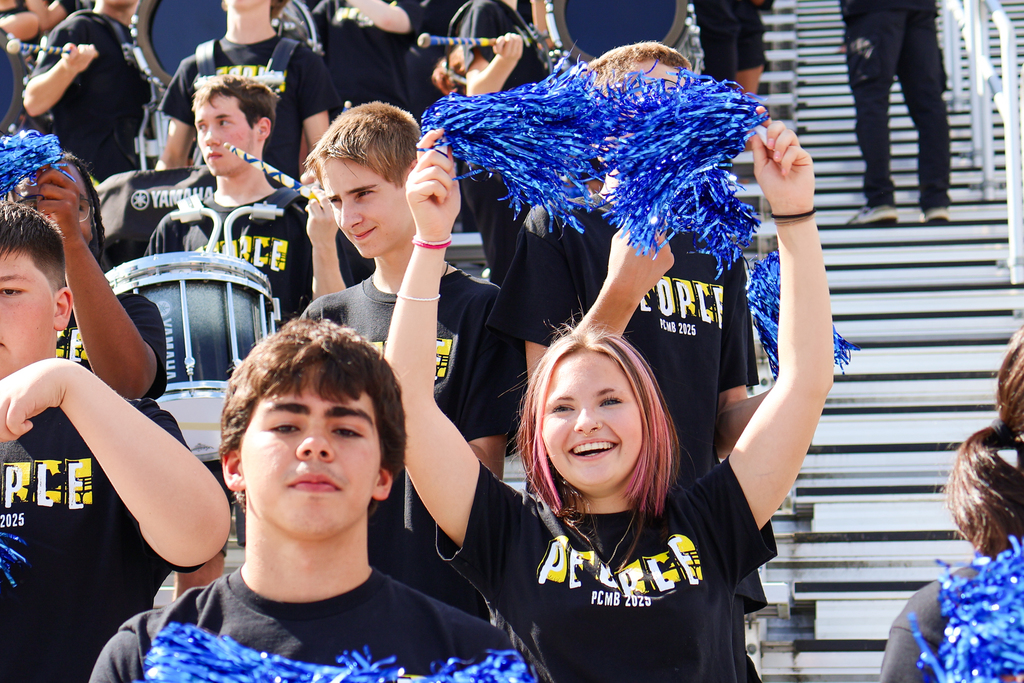 a girl cheers with blue poms poms