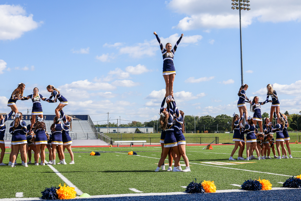 cheerleaders lifted into the air during a routine on a football stadium