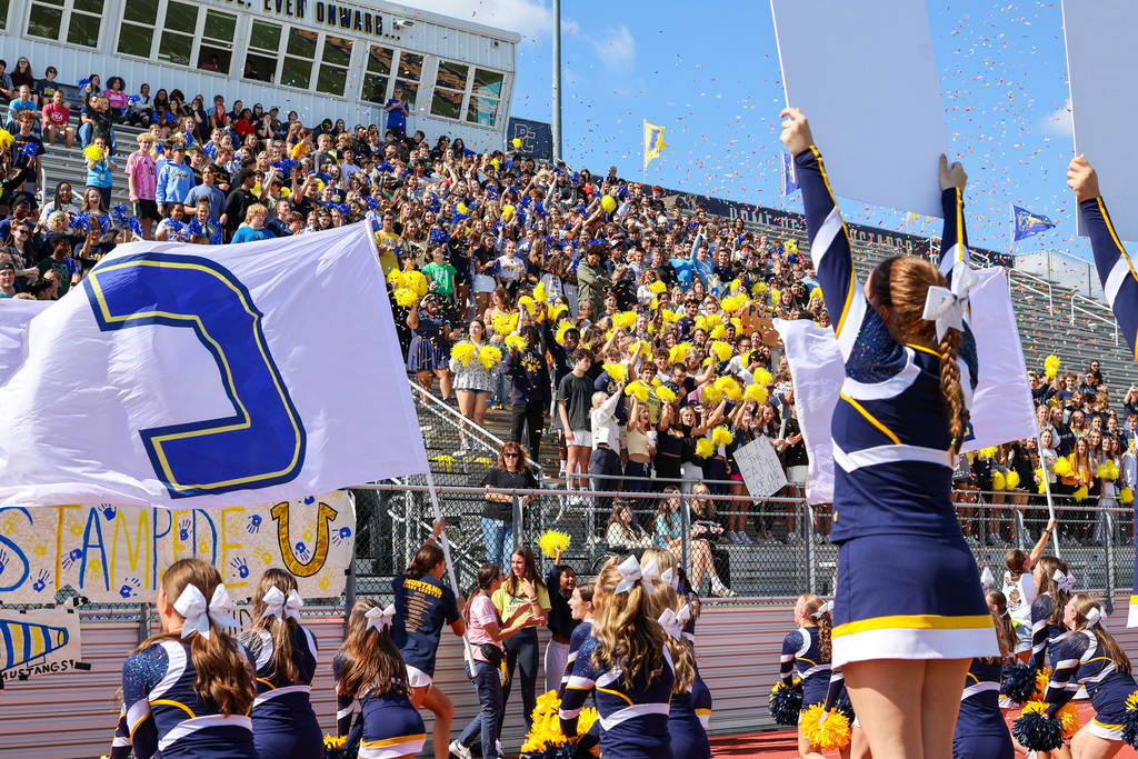 confetti flies through the air in a football stadium full of students