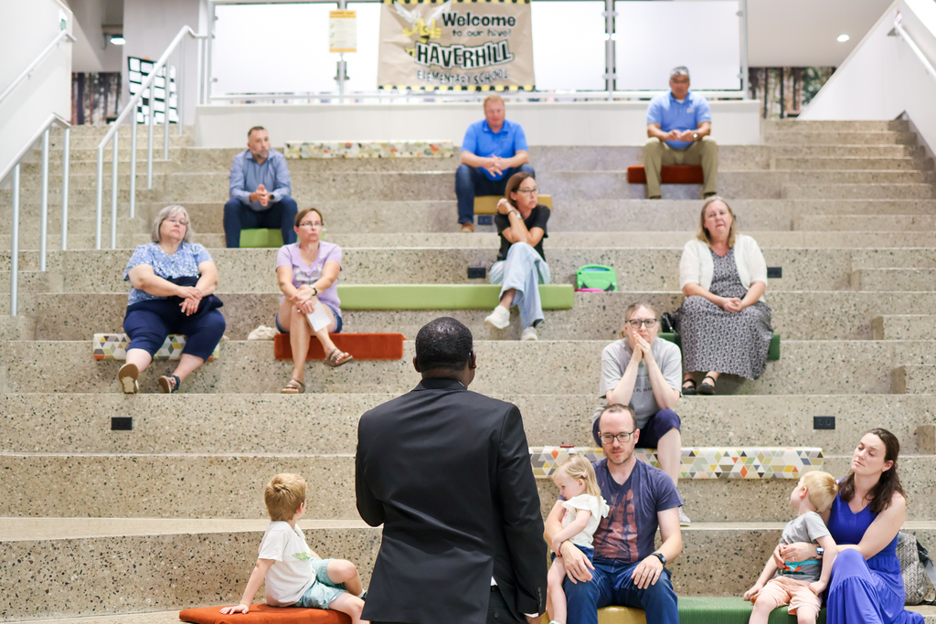 a man speaks to a crowd of people gathered on a large staircase