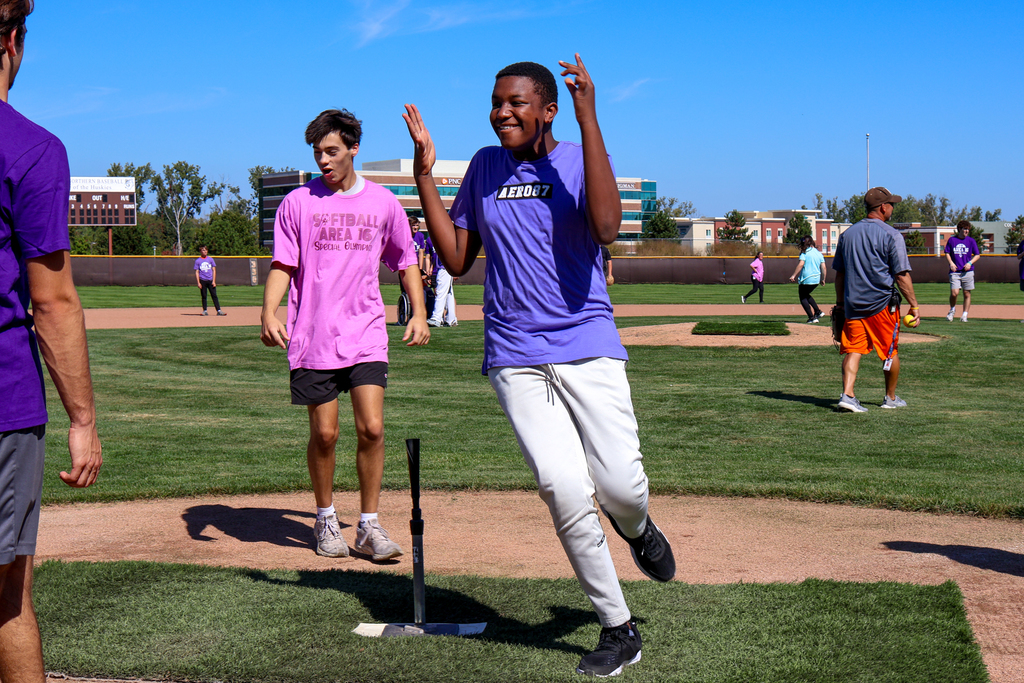 a boy cheers as he crosses home plate on a softball field