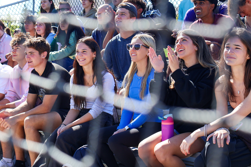 students in stands cheering during a softball game