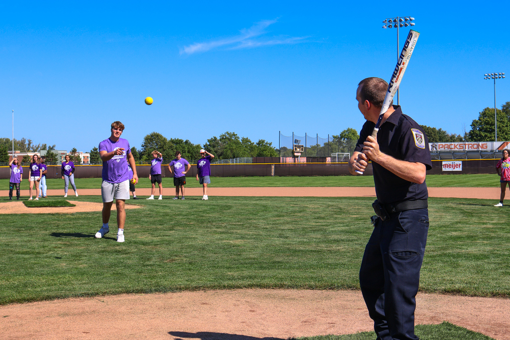 a police officer up to bat on a softball field