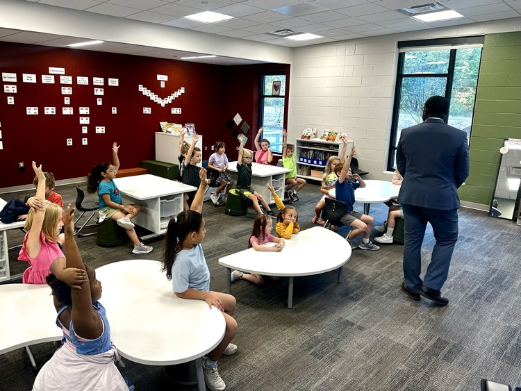kids raising their hands in a classroom