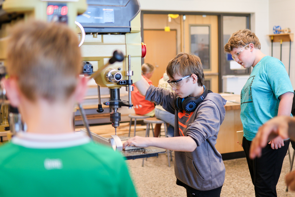 a boy uses a machine in a woodshop
