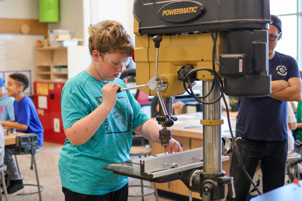 a boy uses a machine in a woodshop