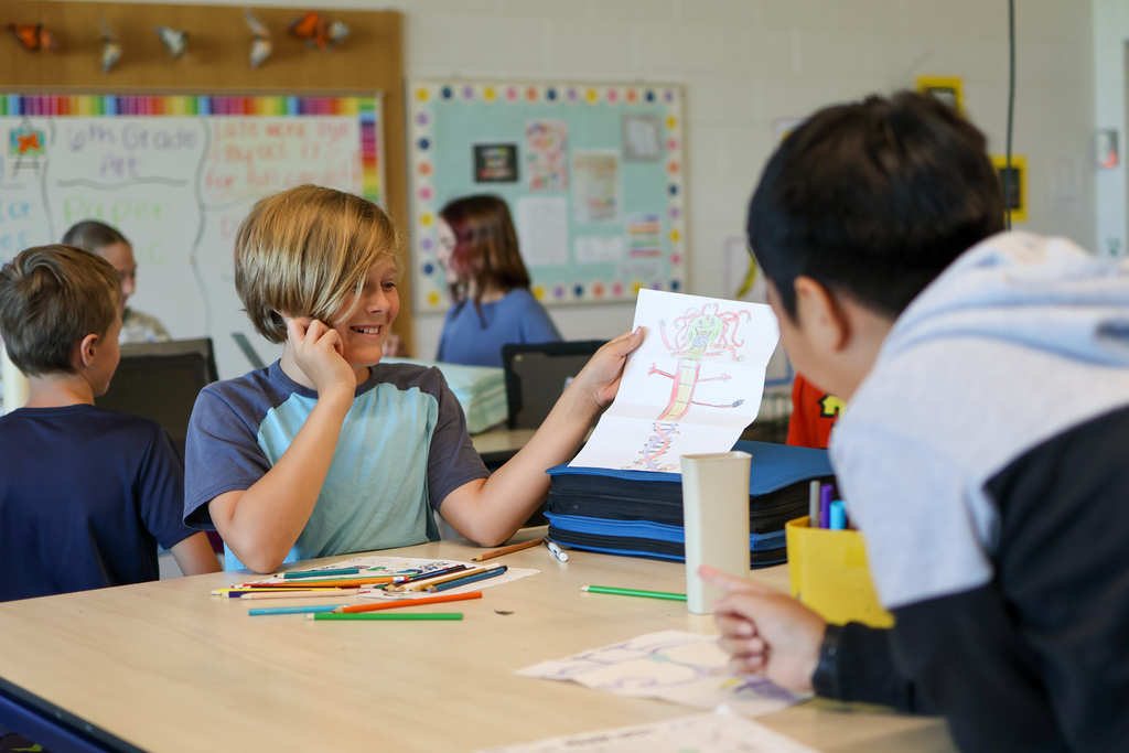 two boys laughing looking at a table in a classroom again