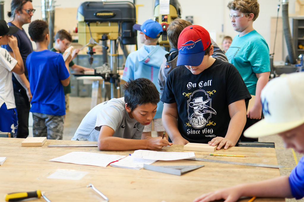 two boys working at a table in a workshop