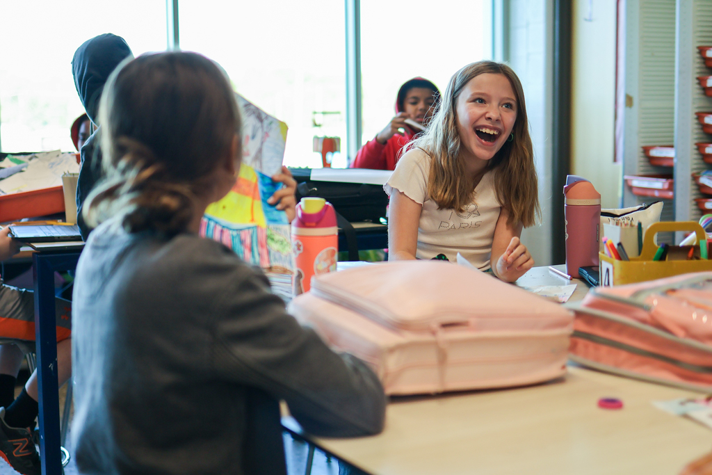 a girl laughing at a table in a classroom