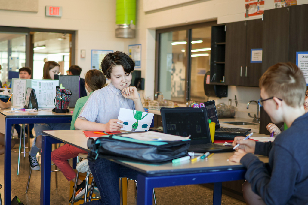 two students working together at a desk in a classroom