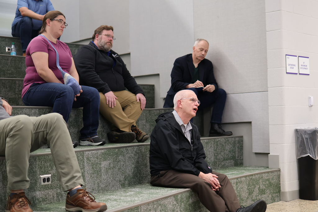 a man asking a question sitting on a large staircase inside a school