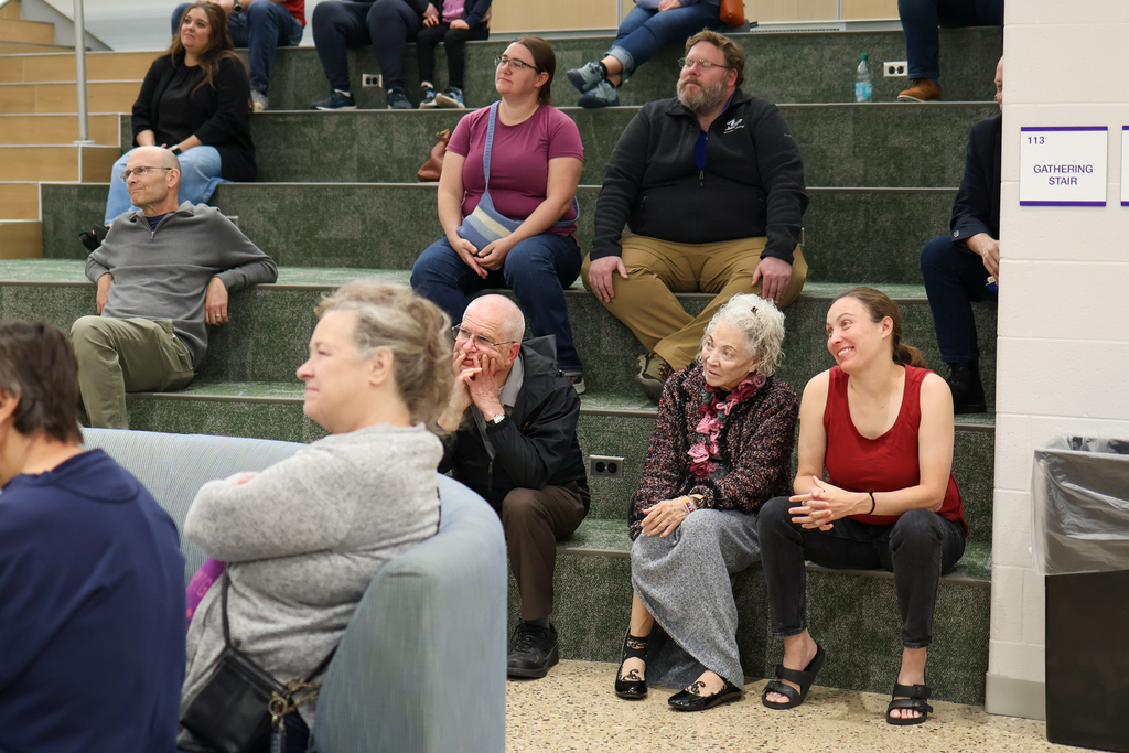 a woman smiles surrounded by others sitting on a large staircase inside a school