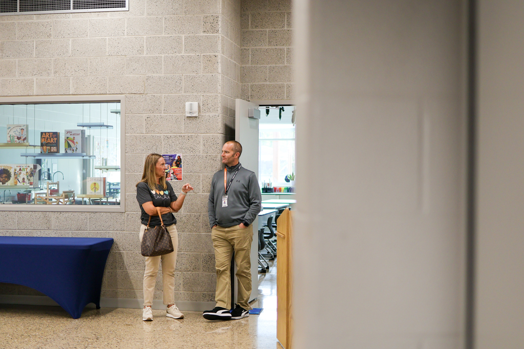 a man and woman stand together inside a school