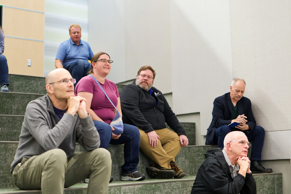 a woman smiles sitting on a large staircase surrounded by others