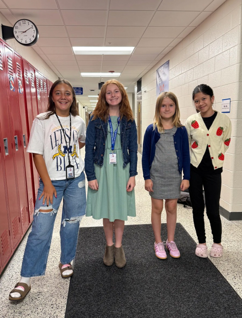 four girls pose for a photo in a school hallway