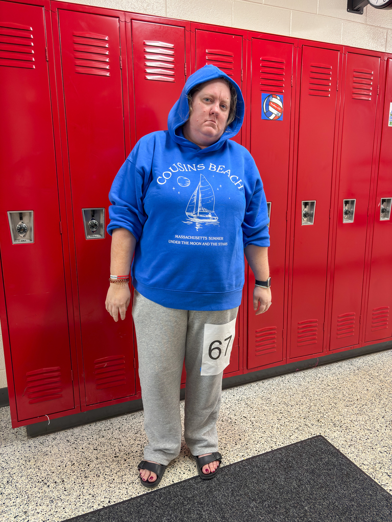 a woman dressed in sweats poses for a photo in a school hallways