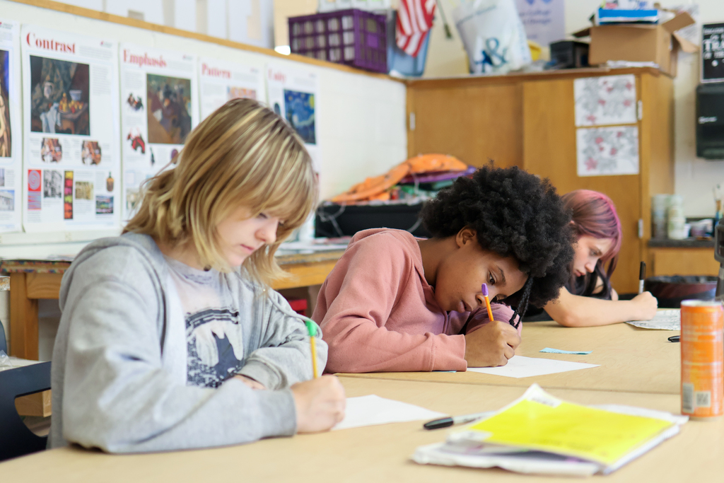 two girls working on artwork in a classroom