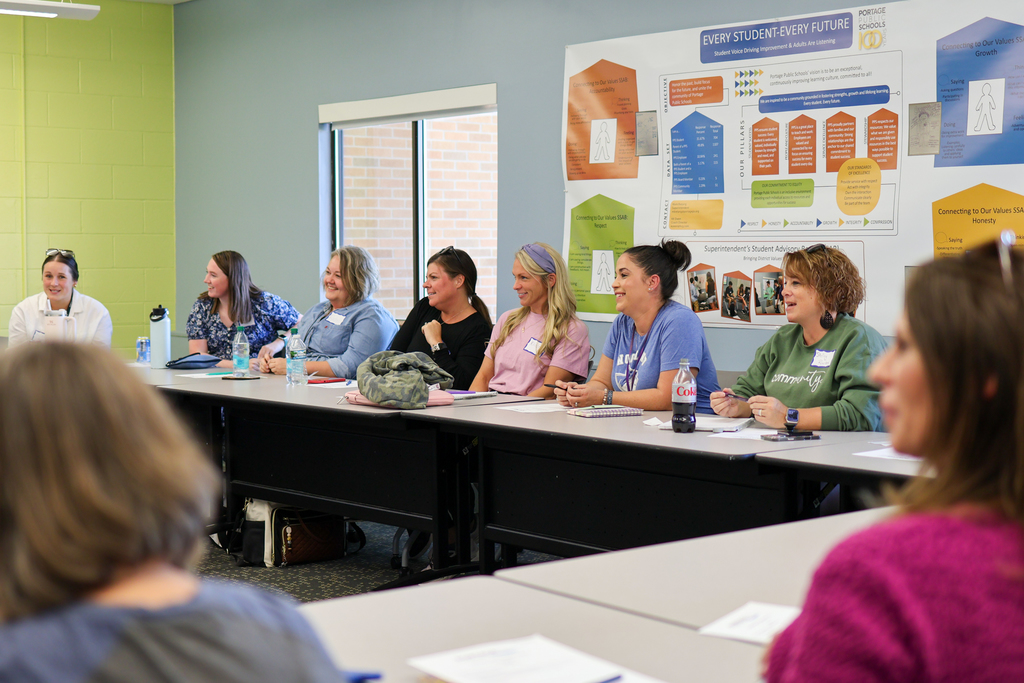 a row of people sitting at a conference room table in a room