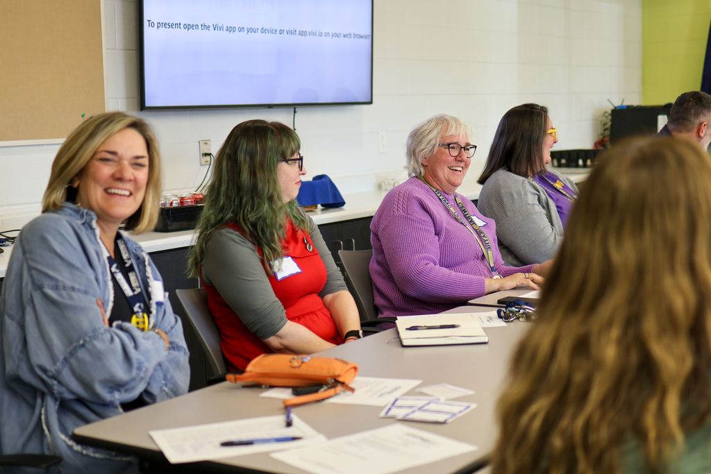 multiple people laughing at a table in a conference room