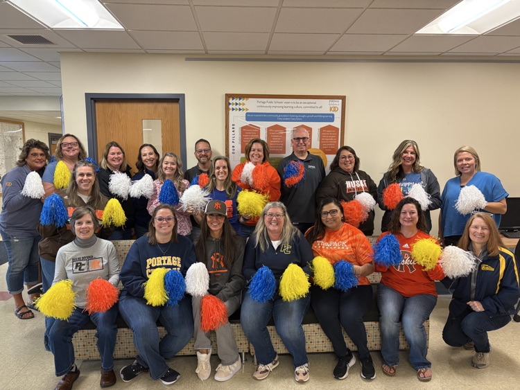 a large group of people posing for a photo and holding Pom poms 