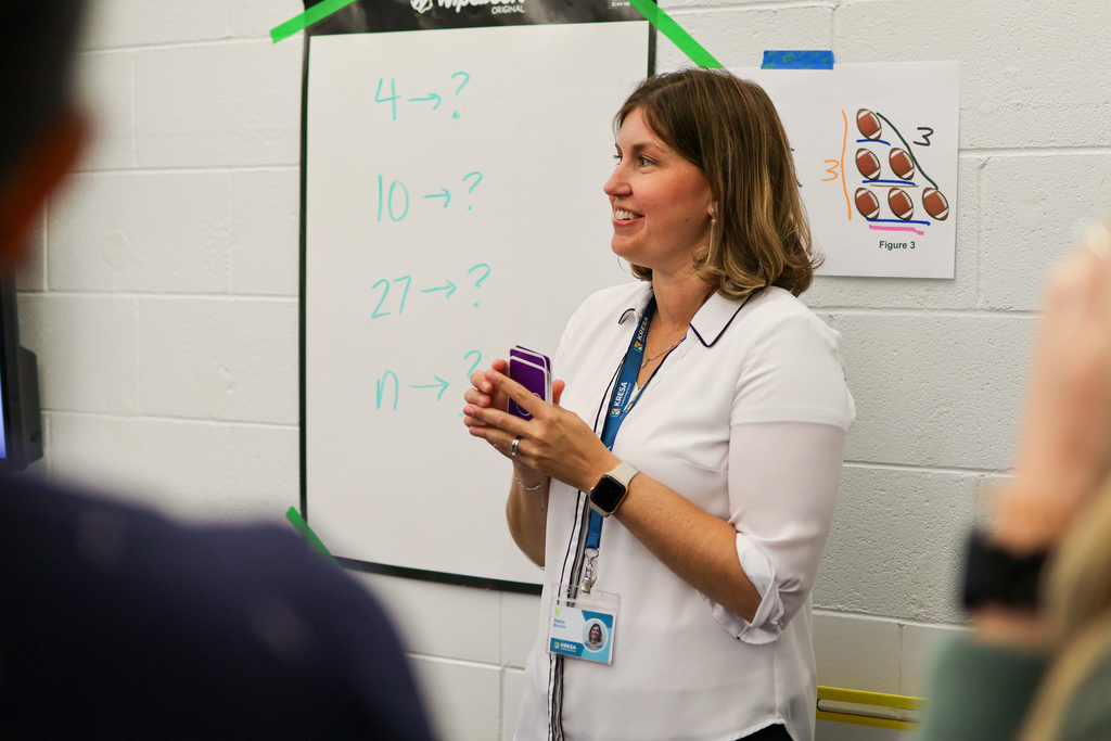 a woman holding cards standing in a classroom