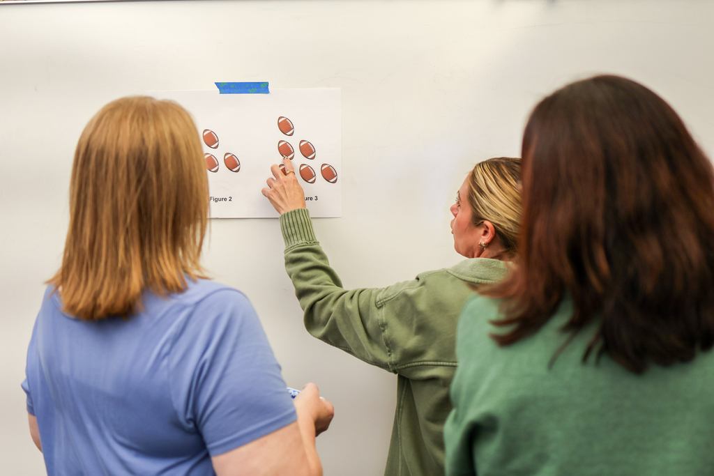 women standing near a whiteboard in a classroom