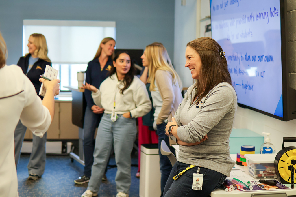 a woman smiles sitting in a classroom
