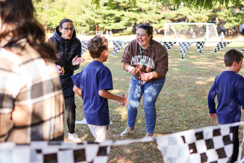 two women encouraging kids running outside