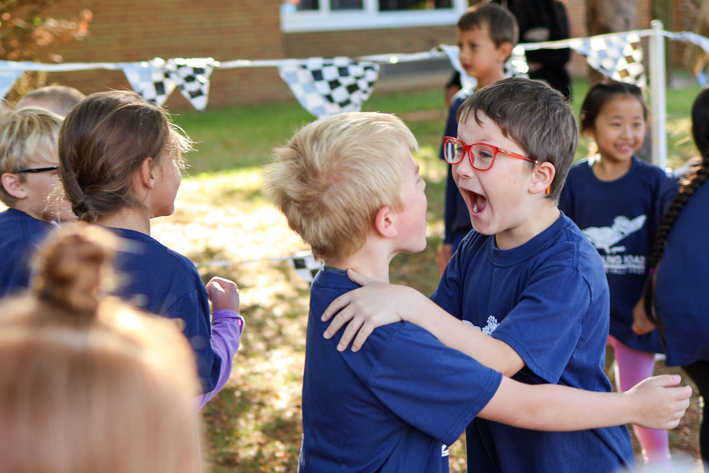two boys cheering and hugging outside a school 