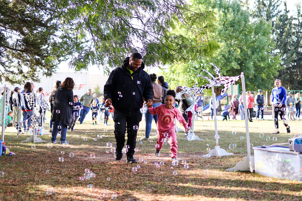 a man and his daughter running outside through bubbles