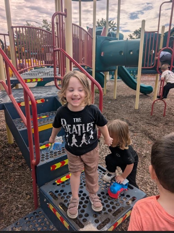 A young girl climbing down a play structure.