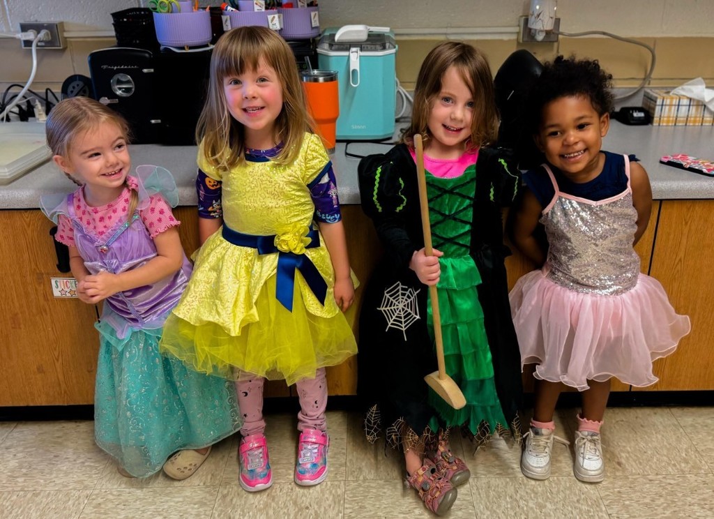Four girls in dress up outfits and smiling.