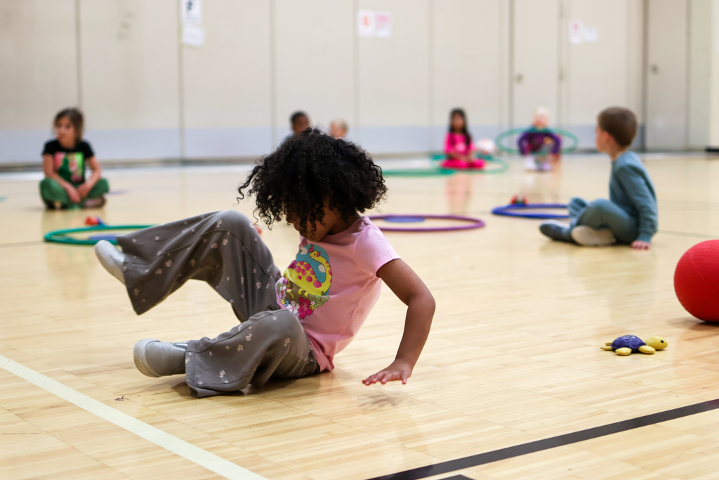 a girl spinning on her butt on a gym floor