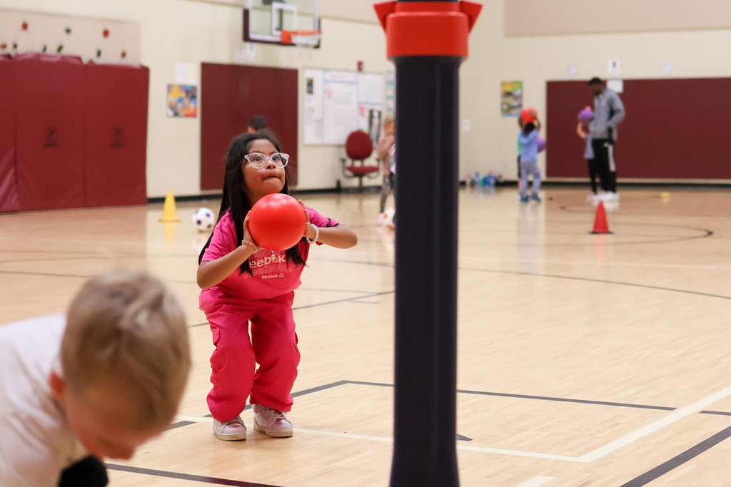 a girl throws a ball into a basketball hoop in a gym
