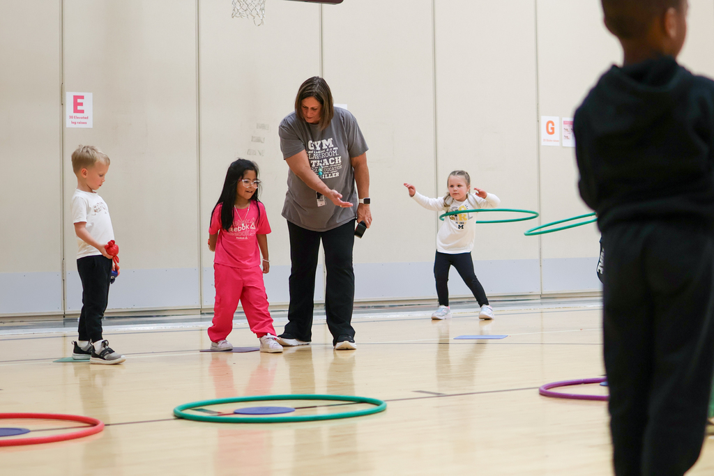 a teacher helps a student throw in a gym