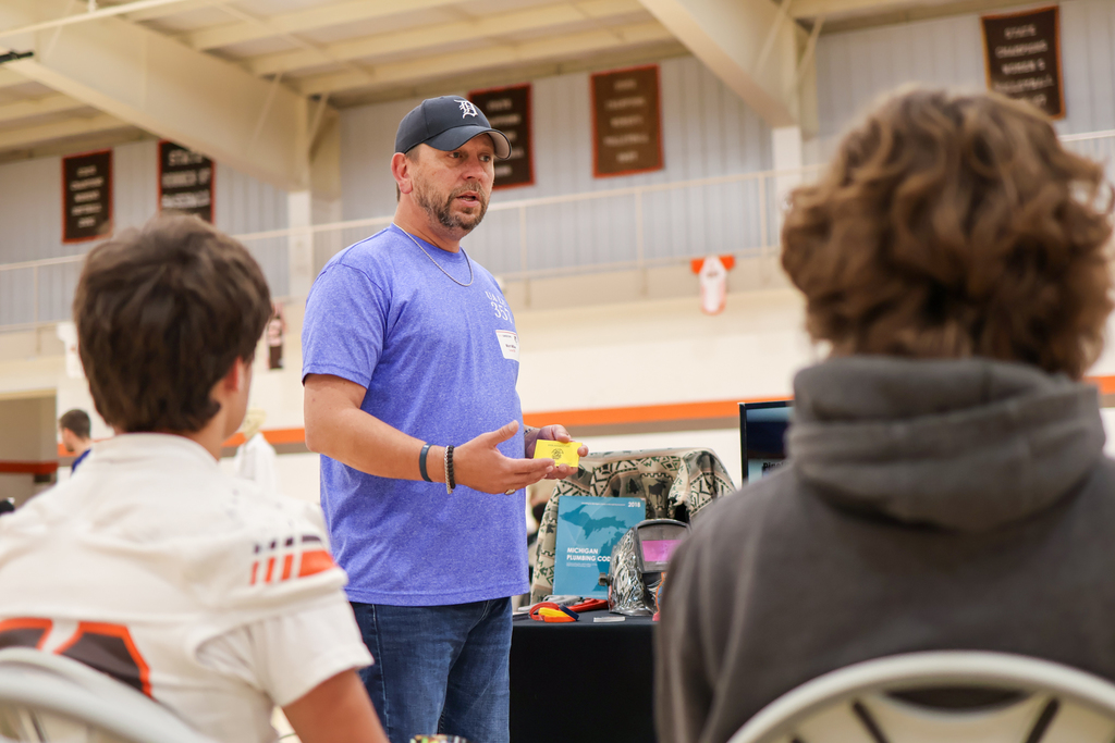 a man speaks to students inside a school gym