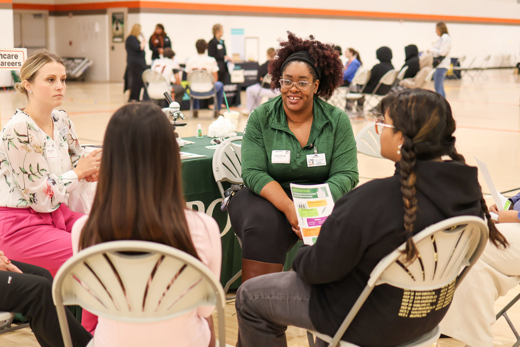 two women sitting in chairs with students in a gym