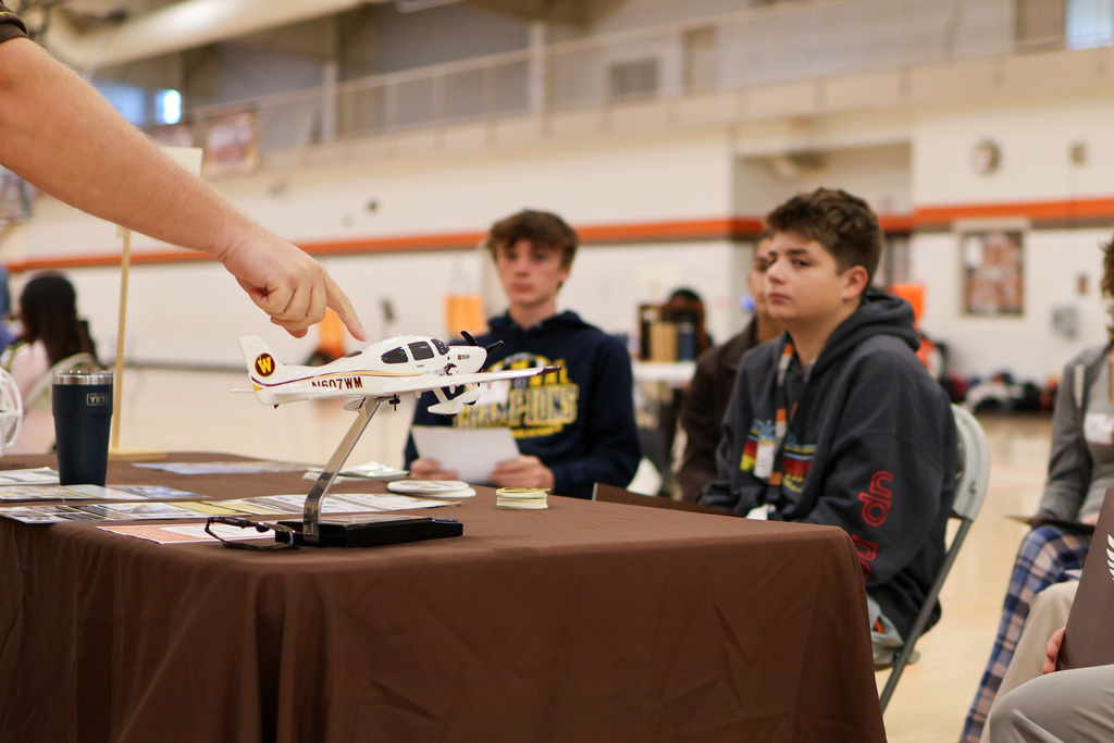 students look on as a man points at a model airplane