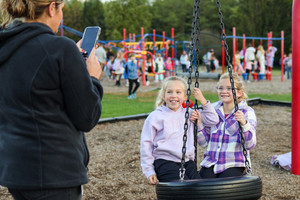 two girls posing for a photo on a tire swing
