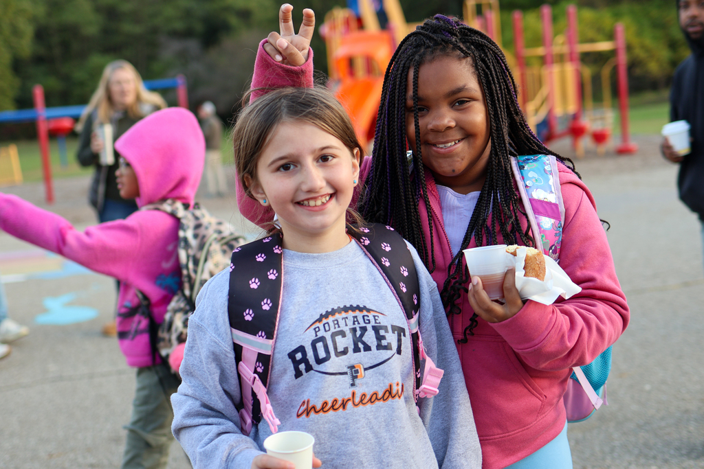 two girls posing for a photo outside a school 